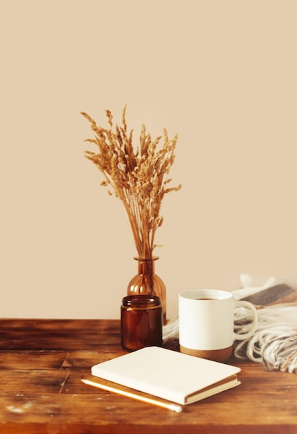 Herfst gezellige compositie. Een kopje koffie, een plaid, een kaars, gedroogde bloemen op een lichte achtergrond.