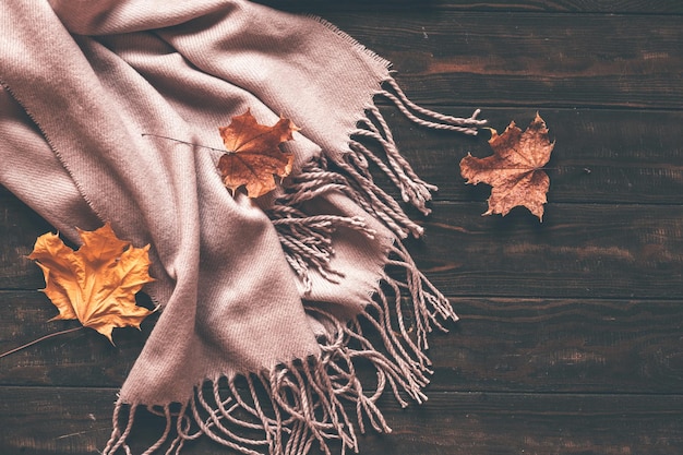 Herfst huis gezellige compositie met een sjaal en esdoorn bladeren op een houten achtergrond