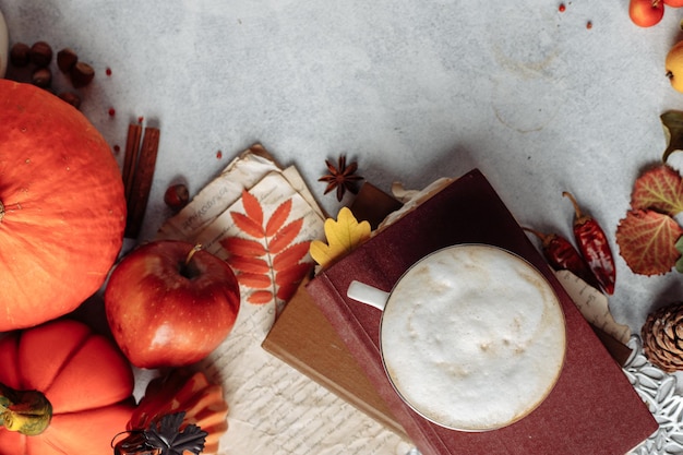 Herfst indeling. een mok koffie, een pompoen, appels en kruiden liggen bij het boek