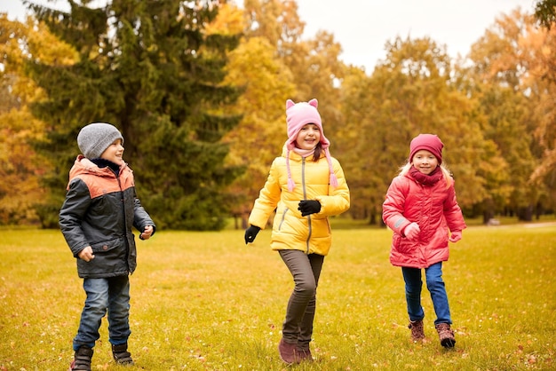 Herfst, jeugd, vrije tijd en mensen concept - groep gelukkige kleine kinderen die tag game spelen en buiten in het park rennen