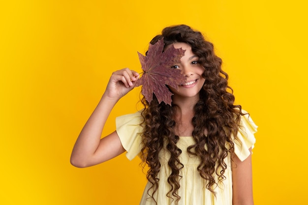 Herfst kinderen Tienermeisje houdt eiken en esdoornblad vast op gele achtergrond Gelukkige positieve en lachende emoties van tienermeisje