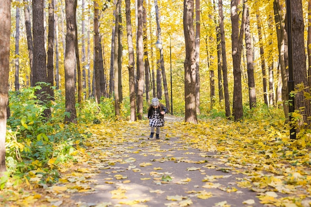 Herfst-, kindertijd- en seizoensconcept - Klein meisje speelt in het herfstpark