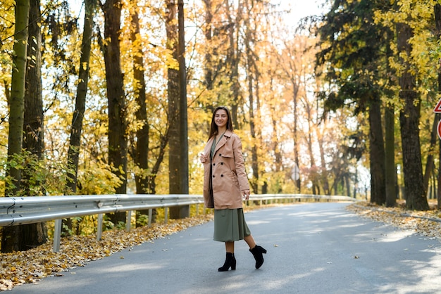 Herfst kleuren. Mooie vrouw in jas poseren in bos langs de weg