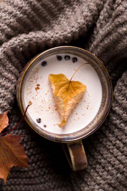 Herfst melk drankje verpakt in een sjaal met een blad binnen.