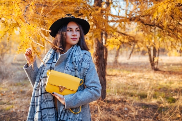 Herfst mode. Jonge vrouw die modieuze uitrusting draagt en beurs in openlucht houdt