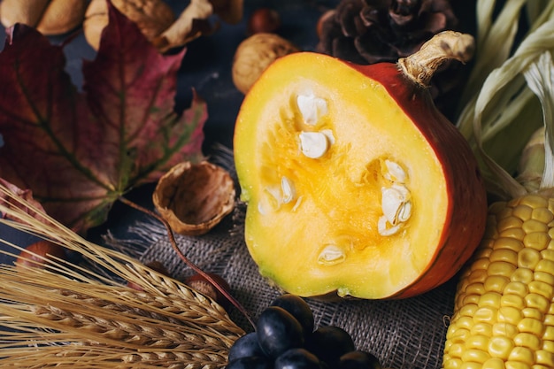 Herfst of Thanksgiving achtergrond met decoratieve pompoen maïs noten druiven en tarwe op donkere stenen tafel oogst stilleven compositie