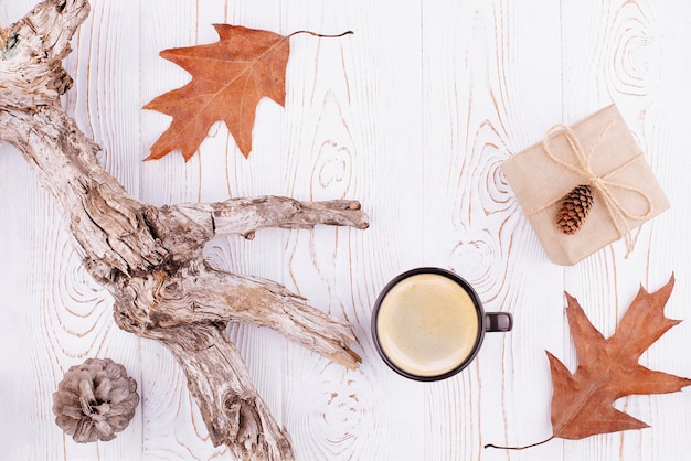 Herfst- of wintercompositie met een kopje koffie herfst droge bladeren drijfhout op een rustieke witgekalkte houten achtergrond Platliggende kopieerruimte