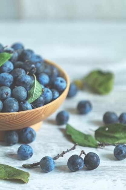 Herfst oogst blauwe sleedoornbessen op een lichte houten tafel achtergrond Kopieer ruimte Natuurlijke remedie