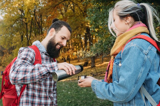 Herfst picknickfeest Gelukkig paar reist met rugzakken, stopte om thee te drinken uit thermoskan