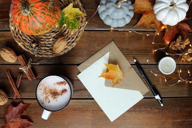 Herfst plat lag compositie met blanco papieren kaart brief envelop koffiekopje sjaal gevallen bladeren op beige achtergrond Herfst hygge stijl bureau tafelblad weergave