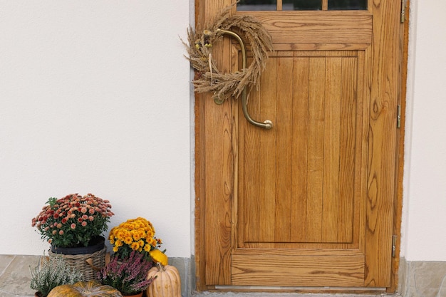 Herfst rustieke krans pompoenen en bloempotten bij houten voordeur Stijlvol herfstdecoratie van de ingang van het boerderijhuis of de veranda Herfstarrangement