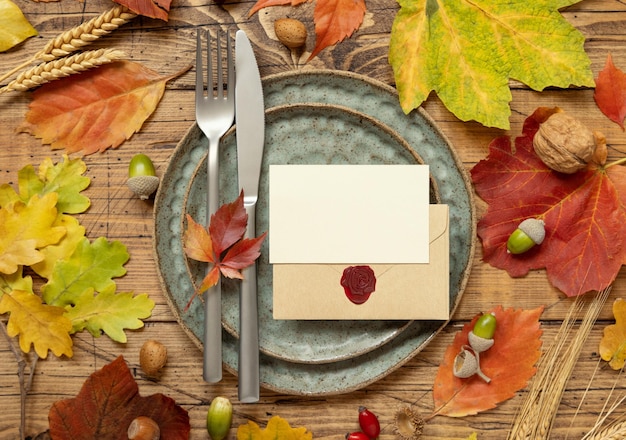 Herfst rustieke tafel met plaatskaart en envelop tussen bladeren en bessen bovenaanzicht mockup