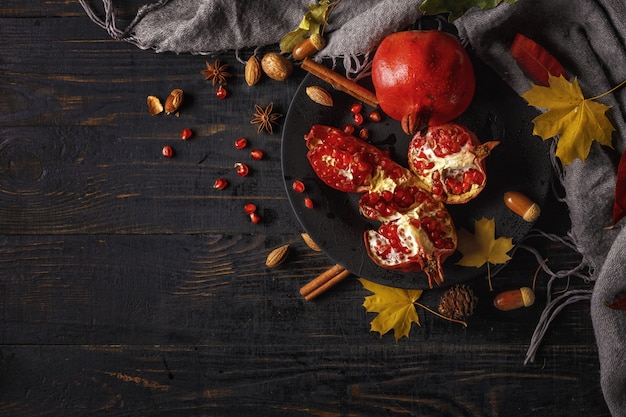 Herfst samenstelling. Granaatappel met noten, kruiden en droge bladeren op een donkere houten tafel. Bovenaanzicht.