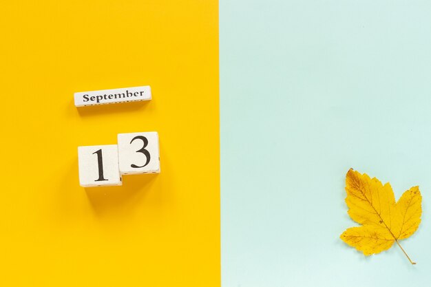 Herfst samenstelling Houten kalender 13 september en gele herfstbladeren op geel blauwe achtergrond