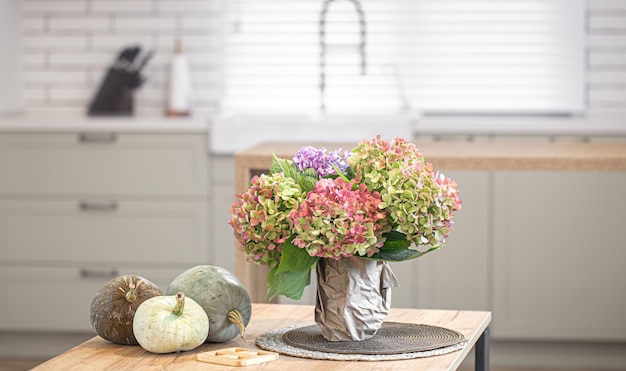 Herfst samenstelling van bloemen van hortensia's en pompoenen op de achtergrond van het interieur van een moderne keuken.