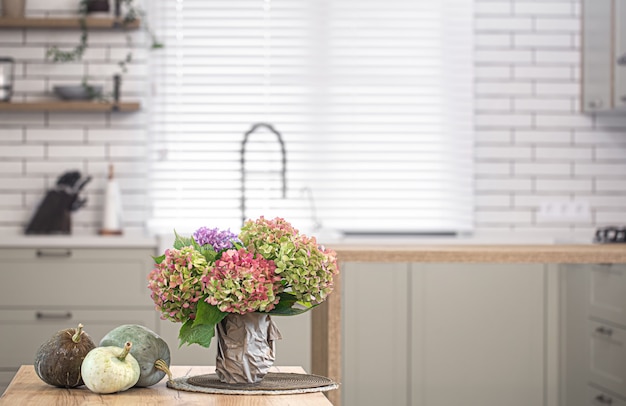 Herfst samenstelling van bloemen van hortensia's en pompoenen op de muur van het interieur van een moderne keuken.