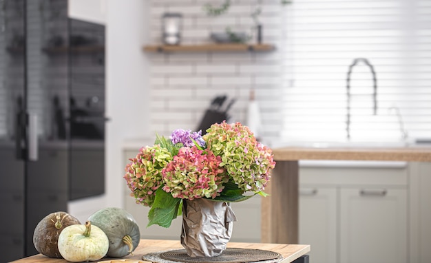 Herfst samenstelling van bloemen van hortensia's en pompoenen op het interieur van een moderne keuken.