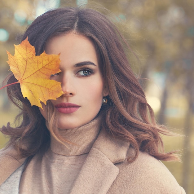 Herfst schoonheid. Perfecte vrouw mannequin met herfst esdoornblad buitenshuis