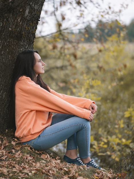 Herfst stemming. Mooi meisje in oranje hoodie in de herfstpark