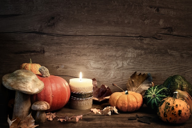 Herfst stilleven met brandende kaars, pumplins en seizoensgebonden decoraties op hout, ruimte