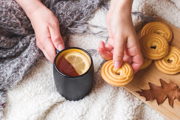 Herfst stilleven met een kopje thee, koekjes, trui en bladeren op een warme zachte deken.