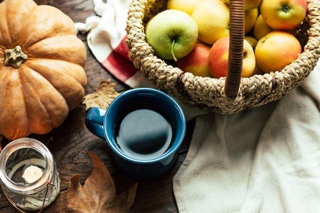 Herfst, thee, pompoenen en appels op een houten tafel