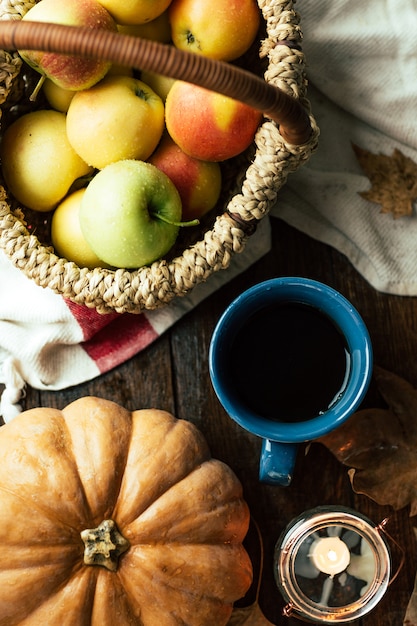 Herfst, thee, pompoenen en appels op een houten tafel