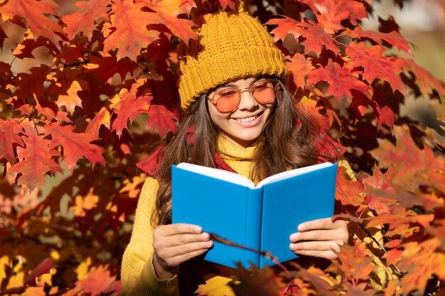 Herfst tiener meisje portret in herfst herfstbladeren glimlachend kind houd boek op herfstbladeren achtergrond