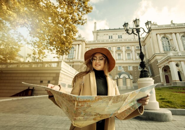 Herfst toerisme. Jonge aantrekkelijke vrouwelijke reiziger wordt geleid door de stadsplattegrond. Mooi meisje op zoek naar richting in de Europese stad. Vakantie en toerisme concept