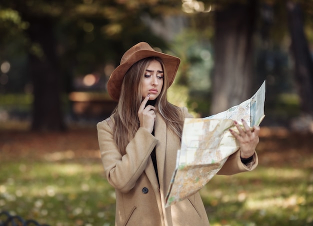 Herfst toerisme. jonge aantrekkelijke vrouwelijke reiziger wordt geleid door de stadsplattegrond.