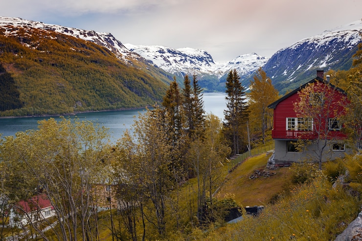 Foto herfst - traditionele noorse houten huizen aan de kust van een meer en bergen op de achtergrond