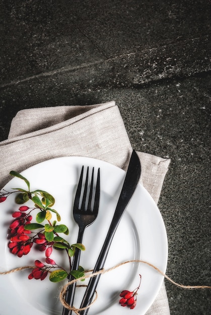 Herfst voedsel scène concept. Thanksgiving-diner, donkere stenen tafel met bestekmes, vork met herfstbessen zoals decoratie. Zwarte scène. Kopieer ruimte bovenaanzicht verticaal