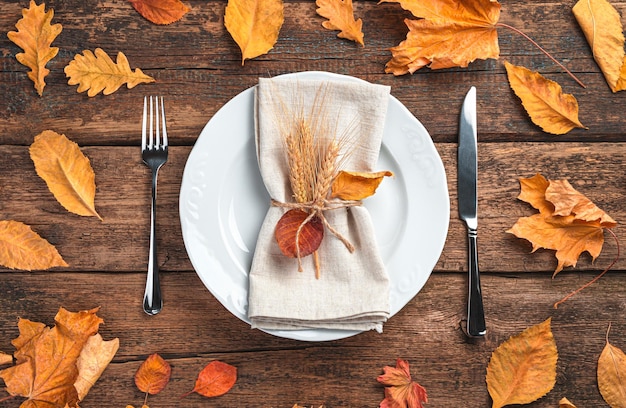 Herfstachtergrond met bestek en herfstbladeren op een houten ondergrond