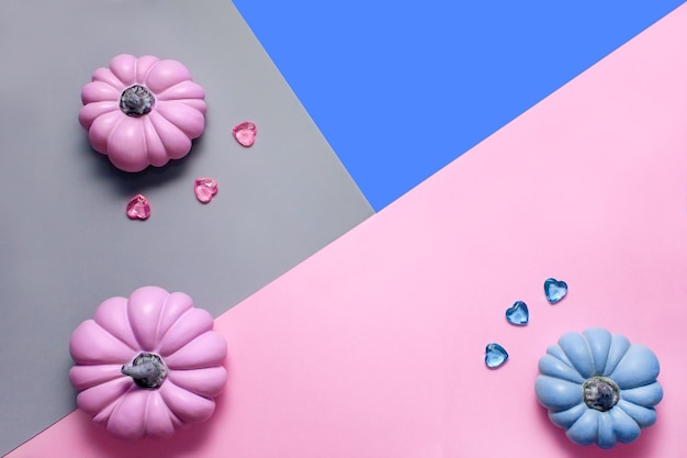 Herfstachtergrond met roze en blauwe pompoenen en glazen hartjes in pasteltinten