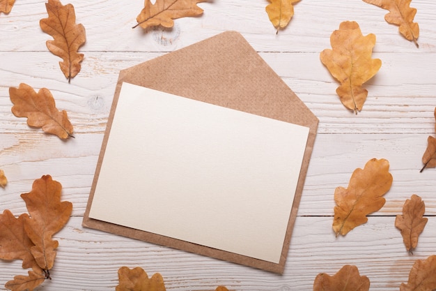 Herfstbladeren en envelop op een witte houten tafel