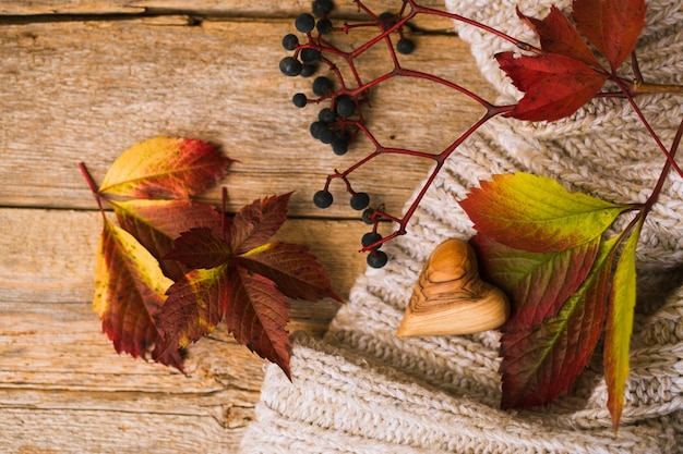 Herfstbladeren en gebreide trui op een houten