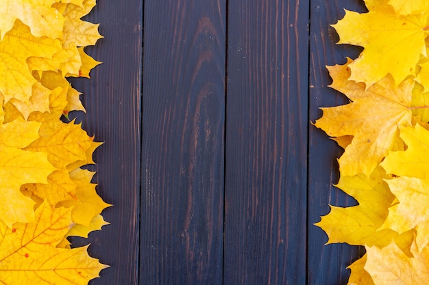 Herfstbladeren frame op houten achtergrond bovenaanzicht Fall Border geel en oranje bladeren vintage houten tafel Kopieer ruimte voor tekst