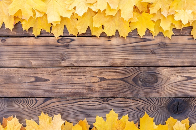 Herfstbladeren frame op houten achtergrond bovenaanzicht fall border geel en oranje bladeren vintage houten tafel kopieer ruimte voor tekst