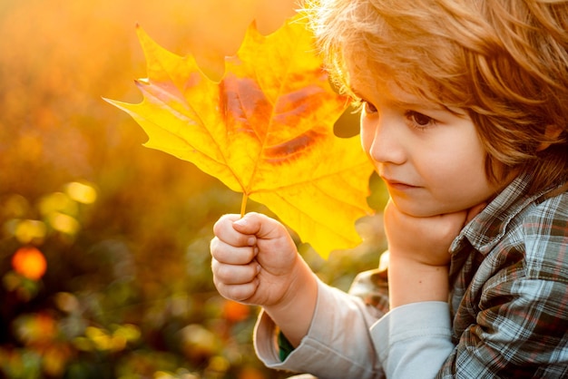 Herfstbladeren jongen jongen dromen kind in warme kleding in de herfst met bladeren