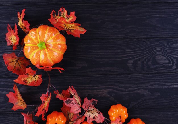 Herfstbladeren met decoratieve pompoenen op hout.