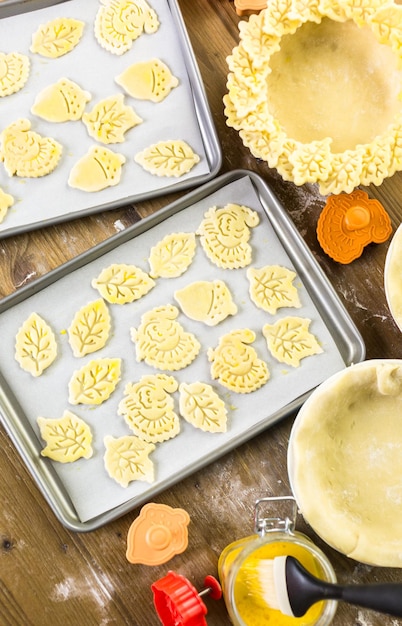 Herfstbladeren uitsnijden met koekjesstempel om pompoentaart te versieren.