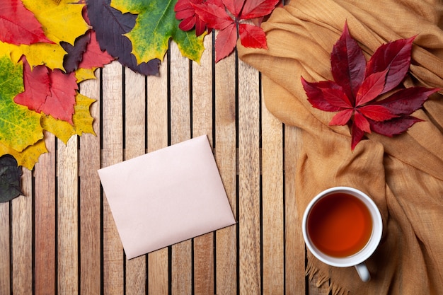 Herfstbladeren, witte theekop op tafel, textielservet, houten achtergrond