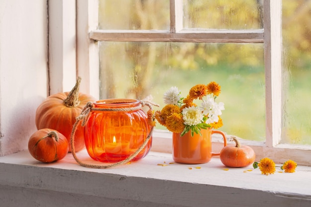 Herfstbloemen en pompoenen op oude witte vensterbank