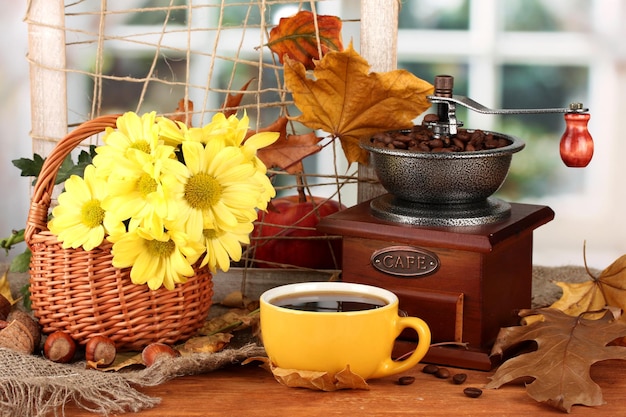 Herfstcompositie koffiemolen bloemen en bladeren op lichte achtergrond