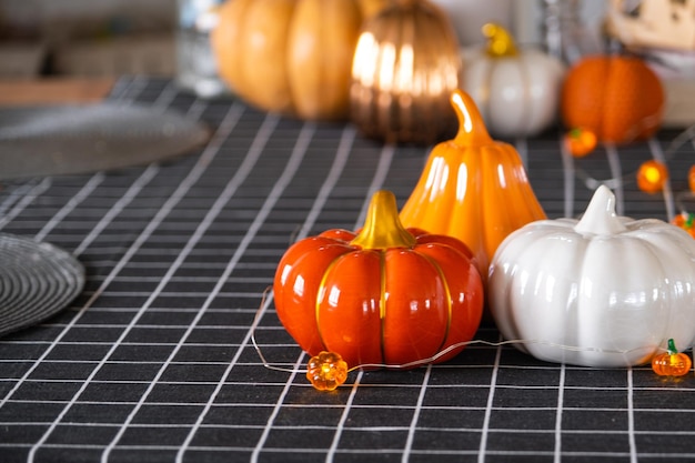 Foto herfstdecor op de keukentafel met een zwart geruit tafelkleed met pompoenslingers latern voor halloween en oogst met beeldje van huis herfststemming in interieur moderne loftstijl