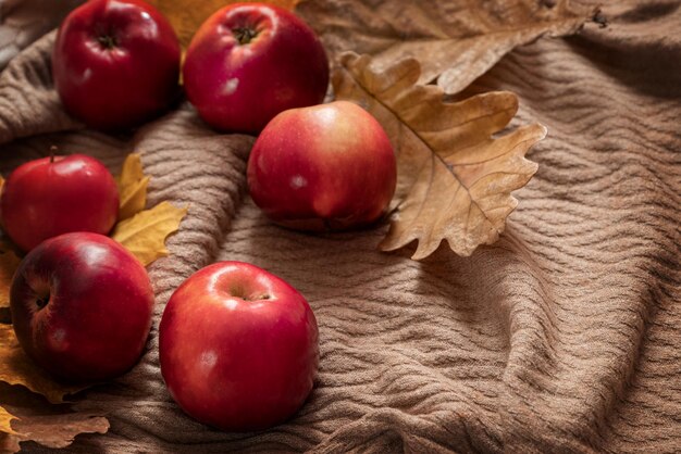 Herfstflaylay-compositie met rode rijpe appels en droge eikenbladeren verspreid over textielachtergrond