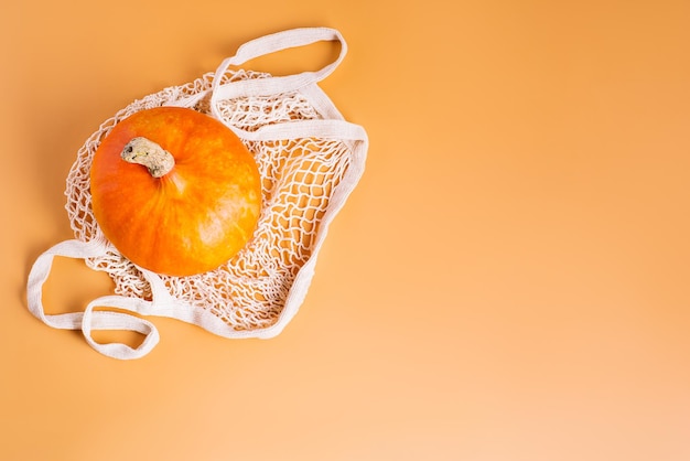 Herfstgroenten halloween pompoenen verschillende pompoenen in een mesh zak van stof oranje achtergrond kopie