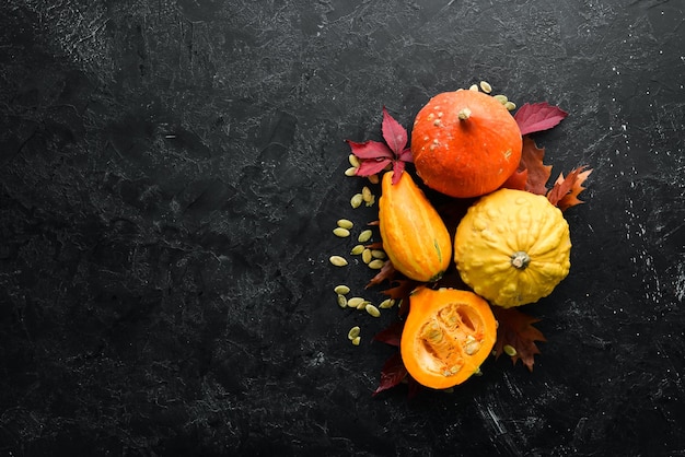 Herfstgroenten Pompoen met pompoenpitten en herfstbladeren plat op een zwarte stenen achtergrond Bovenaanzicht Vrije ruimte voor uw tekst