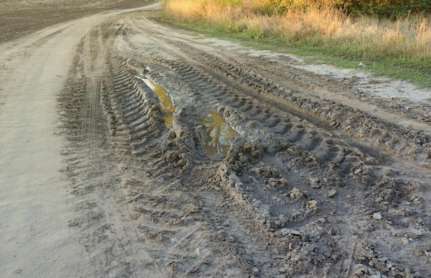 Herfstlandschap met een gebogen weg en sporen van het loopvlak van grote wielen van landbouw