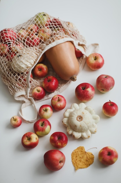 Herfstoogst met pompoen-rode appels in een mesh-shopping eco-tas op een witte achtergrond zonder afval, geen plastic concept